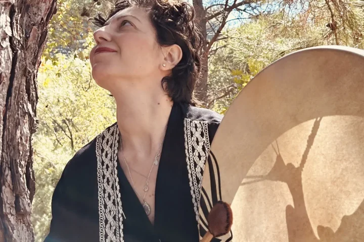 Özbilen Duygu şamanik davulunu tutarken sıcak gülümseme, erk hayvanı çalışması